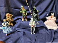 Photo showing six Wizard of Oz character figurines on dark blue fabric background
