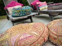 Round embroidered floor pouf with patchwork in beige, orange and pink tones showing detailed stitching and multicolor accents
