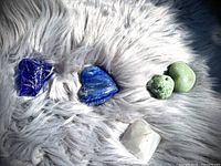 Top-down view showing blue, green, lavender, and white crystals on a grey faux fur surface