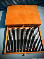 First drawer of the wooden box displaying graphite and black art pencils.