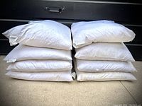 Stack of eight white pillow inserts in two piles of four, showing shape and size.