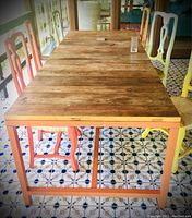 Assembled dining table with reclaimed wood top and orange steel frame, chairs not included