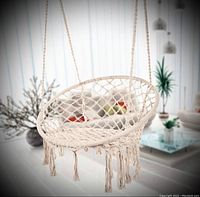 Macrame hanging chair displayed in room, showing netted circular seat with fringe tassels and suspension ropes