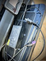 Close-up of power adapter and cables for HP Officejet 7500A printer showing power plug and connectors.