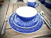 Place setting with stacked dinner plate, salad plate, bowl and mug alongside flatware