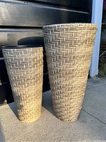 Two conical planters with light beige plastic rattan weave pattern, standing upright outdoors in sunlight