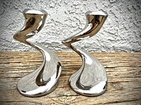 Two hand-polished silver-tone candlesticks with unique twisted swirl design, shown from front without candles.