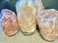 Close-up photo showing multiple Himalayan salt lamps grouped together, each wrapped in plastic.