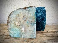 Pair of agate bookends placed side by side on wooden surface, showing polished front faces with intricate mineral patterns and colors.