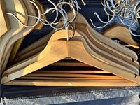 Close-up of wooden coat hangers stacked together showing natural wood finish and metal hooks.