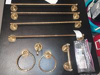 Overview of all hardware items laid out on dark surface: four bars, two rings, hook, holder, hardware bag