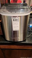 Front view of stainless steel Chef's brand countertop ice maker with clear lid and label on front.