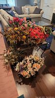 Photo of six faux floral arrangements in baskets and decorative holders on hardwood floor and small table, showing autumn, spring, and neutral themes.