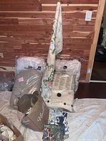 Shows vacuum-sealed comforters and blankets with some fabric pieces on ground against wood-paneled wall.