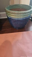 Ceramic planter shown from an angle, displaying the blue and green glazed ribbed exterior surface.