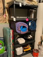 Photo showing entire shelving unit with five shelves loaded with various items including mats, containers, and kitchen appliances (not included).