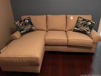 Front view of entire sectional sofa showing chaise on left and two throw pillows on arms