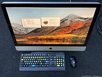 Front view of 27-inch iMac, Lenovo keyboard, HP mouse on gray mat