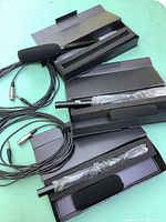 Photo showing three HTDZ HT-320A shotgun microphones with foam windshields, long attached cables with XLR and 1/4 connectors, and their protective boxes with foam inserts.