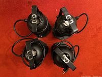 Overhead view of four black PAR can stage lights showing tops with handles and attached cords.