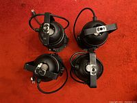 Overhead view of 4 black metal par can stage lights with attached power cables and mounting yokes.