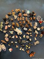 Photo showing a broad collection of 70+ ceramic miniature animals and figurines laid out from a top-down view. Various farm animals and small footwear figurines visible.