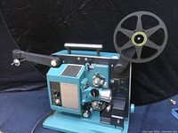 Full side view of the Bell & Howell FILMOSOUND Specialist 16mm projector showing the metal body, reel arm with reel attached, and control panel.
