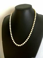 Front view of the vintage cultured pearl necklace displayed on black bust to show length and uniform pearl arrangement.