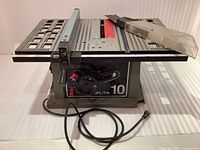 Front view of the Delta 10 portable table saw showing tabletop, power cord, safety shield set on the right side.