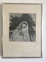 Framed black and white print showing a young girl with headscarf, outdoors with bundles of straw behind her, visible full framed piece.