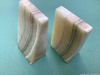 Two wedge-shaped natural onyx stone bookends shown from angle displaying their height and distinct banding lines.