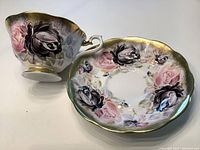 Teacup and saucer set displayed side by side showing overall pattern and gold trim