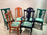Front view of six solid hardwood chairs painted in different colors with unique bird patterned fabric upholstery.