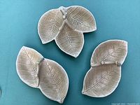 Top view of three vintage SylvaC ceramic leaf serving dishes arranged on blue surface, showing overall shapes and textures