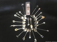 Overhead photo showing all 22 vintage collector souvenir spoons arranged in a circle, highlighting the variety of designs and sizes.