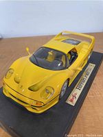 Front angle of yellow 1/18 die cast Ferrari F50 model on black display stand with Maisto and Ferrari F50 labeling.