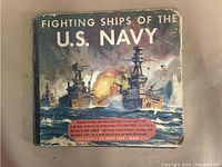 Front cover of the book 'Fighting Ships of the U.S. Navy' showing artwork of several Navy warships with a battle scene, heavily worn and creased edges.