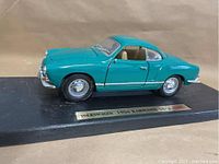 Side view of teal blue 1966 Volkswagen Karmann Ghia die cast model on black display stand with brass label plaque.