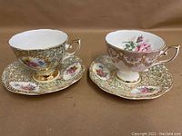 Two English bone china teacups and saucers by Royal Standard showing floral and gold trim decoration on a brown background.