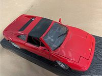 Red 1/18 scale Ferrari 348-ts diecast car model on a black display stand, angled top front view.