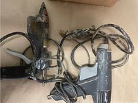 Photo showing two black hot melt glue guns with attached cords, one noticeably frayed on the cord of the Minimatic model.