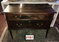 Front view of server showing two drawers, brass handles and inlaid medallion on lower drawer