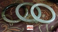 All three jade bangles side by side on patterned fabric