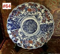 Full view of Antique Imari pottery plate showing scalloped rim, floral and geometric patterns in blue and orange colors, set against white background
