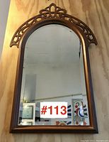 Front view of the walnut framed mirror showing arched shape and carved details.