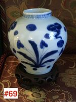 Front view of blue and white pottery vase on carved base