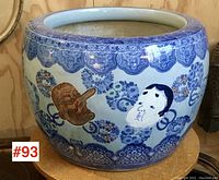 Front view of the large round stoneware jardiniere showing blue floral border and two painted human faces