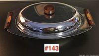 Front view of covered serving dish closed showing chrome lid with bakelite knob and bakelite handles on sides.