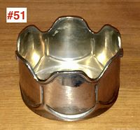 Top-down view of silver plated wine bottle coaster showing scalloped edges and polished finish.