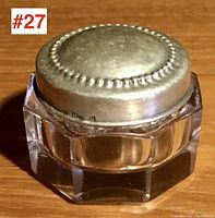 Front view of closed jar showing silver lid and octagonal glass base.